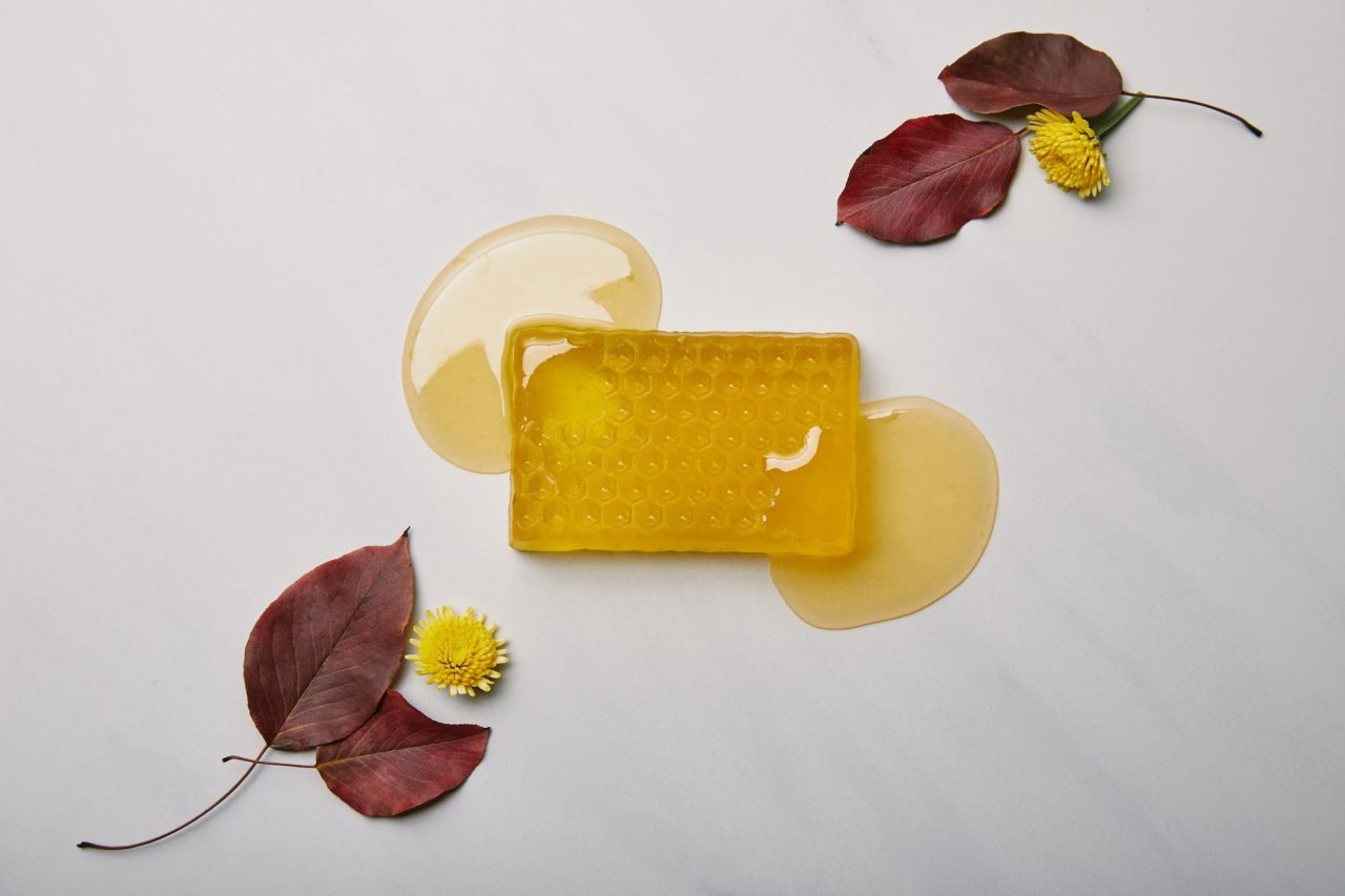 top-view-of-handmade-soap-in-shape-of-honeycomb-with-dandelions-and-leaves-on-white-marble-surface.jpg